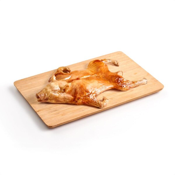 A whole, roasted suckling pig splayed stomach-side down across a wooden cutting board.