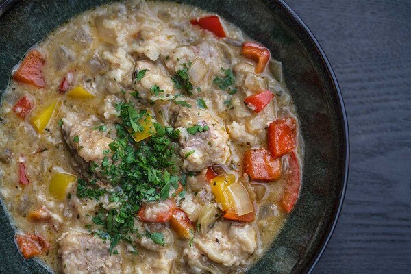 Alligator tenderloin tail meat stew with vegetables in clear broth in a bowl