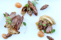 Cooked, sliced Beeler’s pure pork cheeks with roasted fennel, brown sauce, green herbs, white rectangular plate