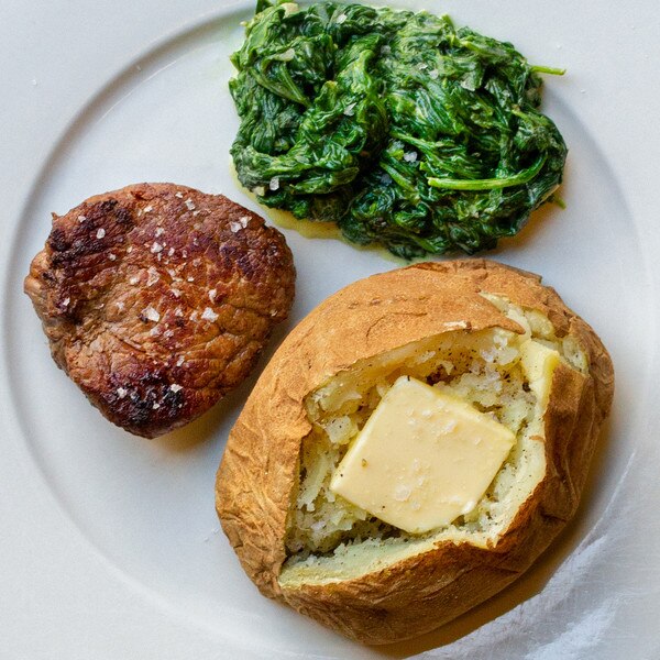 grilled grass-fed Angus beef tenderloin filet on a plate with creamed spinach & buttered baked potato