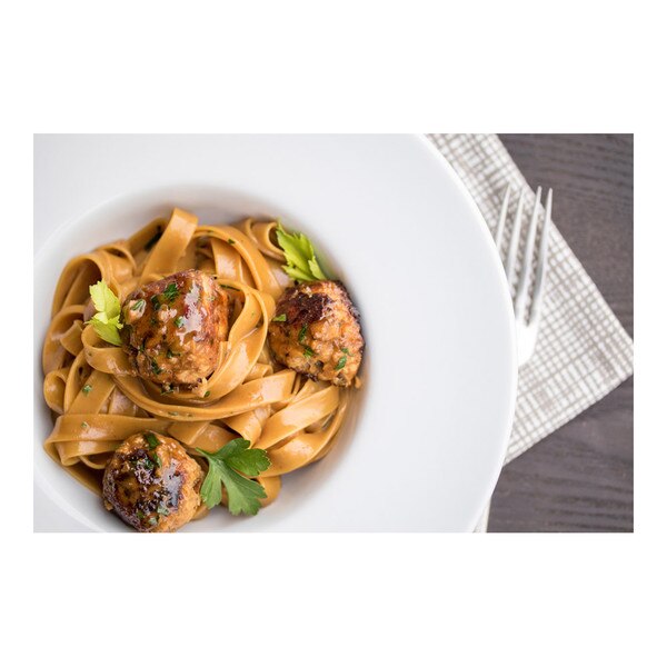 3 rabbit meatballs, tagliatelle pasta, parsley, white bowl, fork, grid-patterned napkin