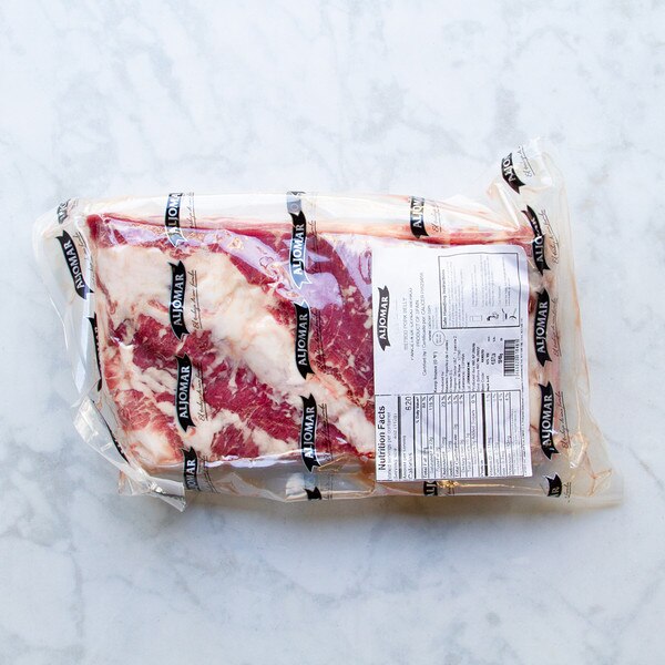 Vacuum sealed package of Spanish Iberico pork belly on marble background