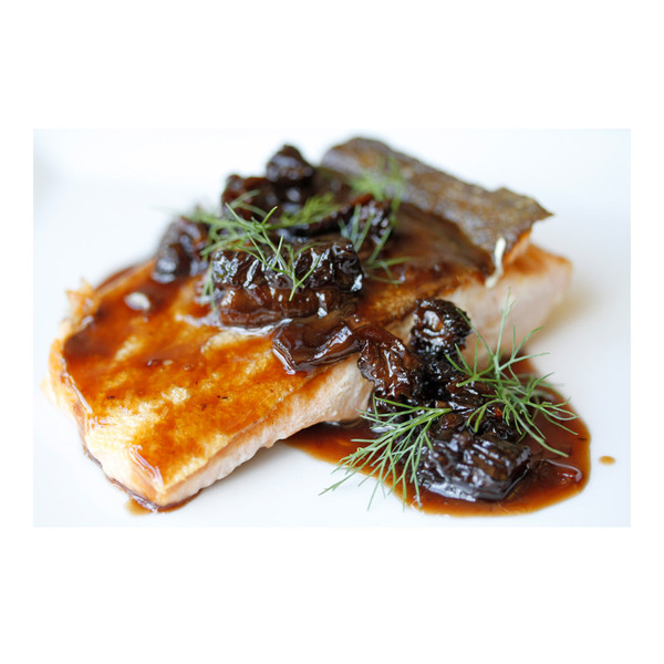 Cooked wild keta salmon fillet, skin side up, topped with a dark brown mushroom sauce & fresh herb sprigs