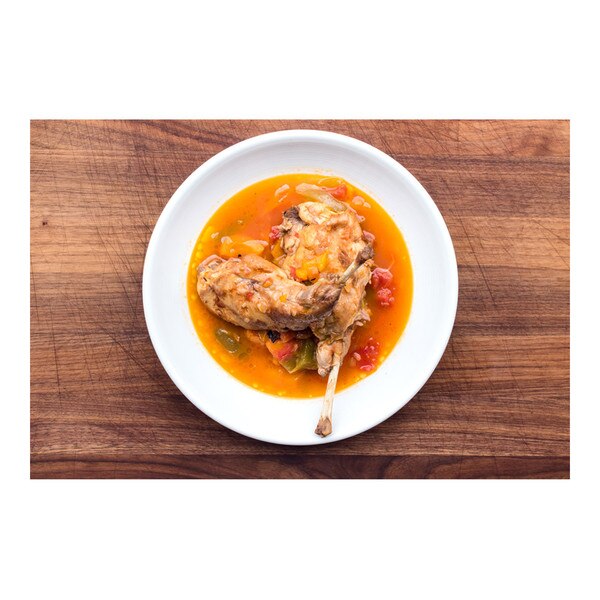 2 braised rabbit legs, red pepper & tomato piperade broth, white bowl, brown wood background