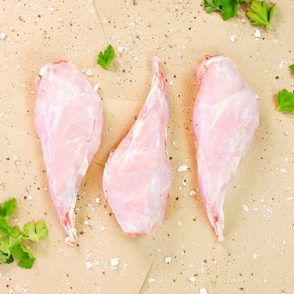 3 raw rabbit hind leg quarters on brown butcher paper sprinkled with salt, pepper, parsley sprigs