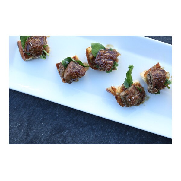 5 rabbit liver crostini on brioche toast with watercress & brown shallot sauce, rectangular plate on slate gray background