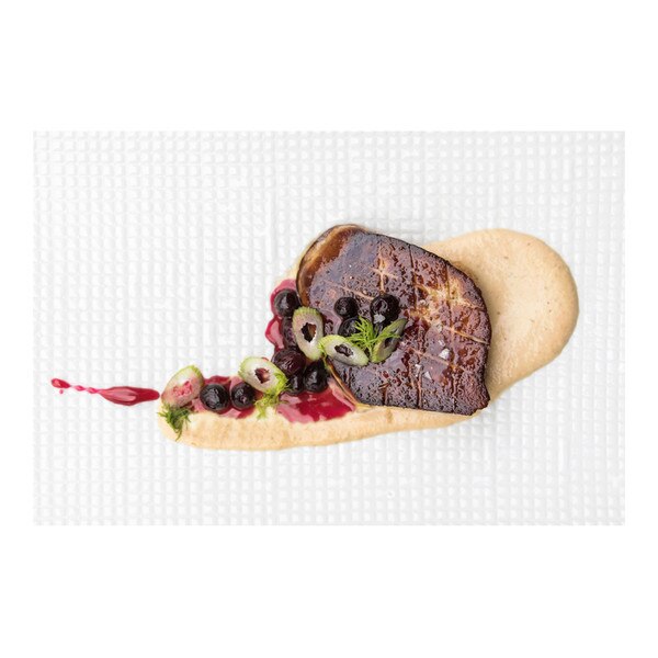 Beige sauce beneath a slice of seared grade B foie gras topped with blueberry sauce, whole blueberries & fennel slices