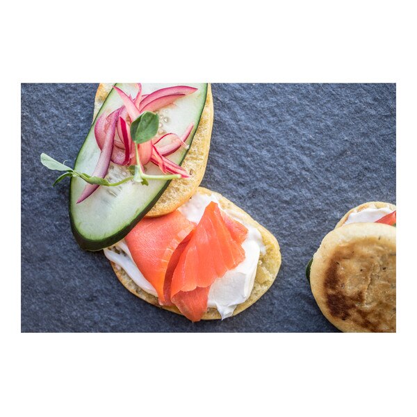 Pink wild-caught sockeye salmon, white crème fraiche, cucumber slice, red onion slivers and microgreens on seed-flecked buns