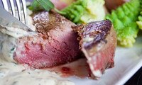 Knife & fork cutting into cooked grain-fed veal filet mignon, tarragon cream sauce, romanesco, white plate