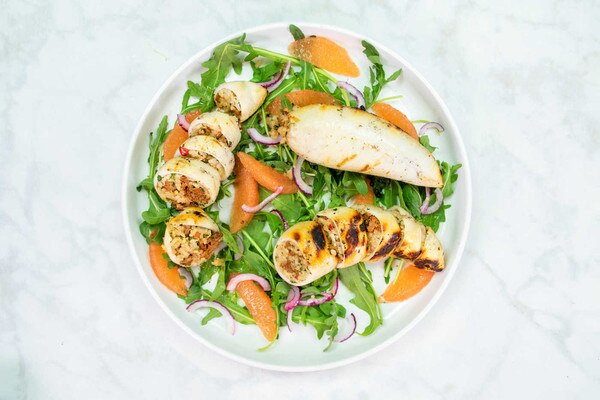 Grilled Spanish squid stuffed with sausage, rice, and peppers on a bed of spring greens and grapefruit