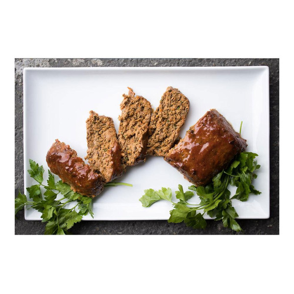 Sliced, glazed, cooked wild boar meat loaf with parsley sprigs on white rectangular plate