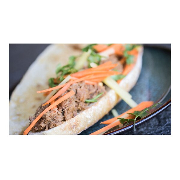 Braised wild boar boneless leg meat sandwich, carrots, pineapple, cilantro leaves, torpedo roll, on blue plate